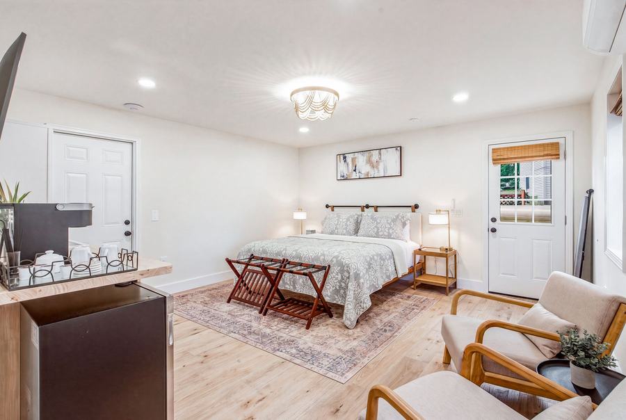 Bright king bedroom with seating area, bedside lamps, and access to the outdoor deck