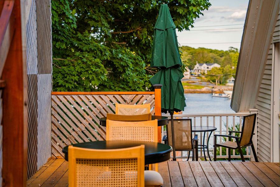 Outdoor deck with chairs, umbrella, and a scenic view of the harbor.